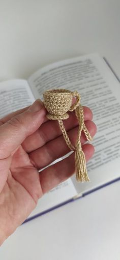 a hand holding a crocheted ring in front of an open book