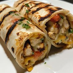 two burritos on a plate with cheese and tomatoes