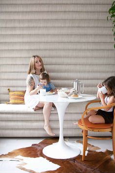 a woman sitting at a table with two children