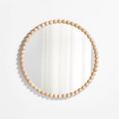 a round wooden beaded mirror hanging on a wall