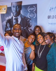 a group of people taking a selfie in front of a movie poster with one person holding up a cell phone