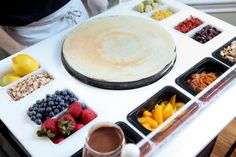 a person standing in front of a table with food on it and bowls of fruit