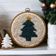 a cross stitch christmas tree ornament on a shelf