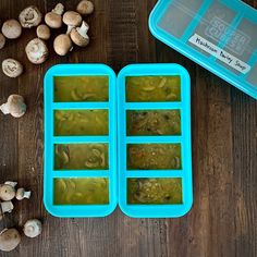 two ice trays filled with green liquid next to mushrooms on a wooden table,