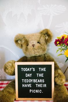 a teddy bear holding a sign that says today's the day the teddy bears have their picnic