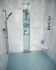 a bathroom with blue and white tiles on the floor, shower stall and shelves in the wall