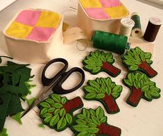 some green and pink decorations sitting on top of a table next to sewing thread, scissors and spools