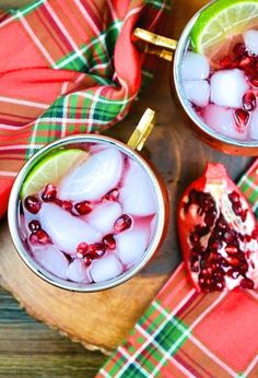 two glasses filled with ice and pomegranate on top of a wooden table