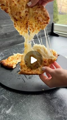 someone is taking a slice of pizza from the plate on the table with their hands