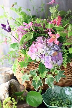 flowers and plants are arranged in baskets on the table