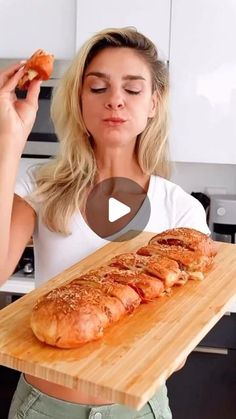 a woman holding a wooden cutting board with some food on it