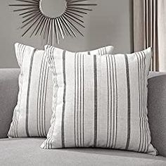 two pillows sitting on top of a couch in front of a sunburst mirror