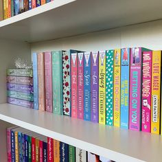 a row of colorful books sitting on top of a white book shelf next to each other