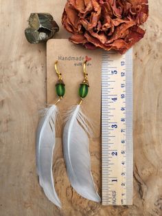 Get the elegance and simplicity of beautiful natural feathers with a little added glitz and a splash of color. These one-of-a-kind earrings are hand made with love from natural white to light grey colored feathers. The added gold and green bead accents create a beautiful, lightweight piece for your lobes that is both simple and chic. The gold colored lever back hardware is a cinch to get on and stay secured all day long. The hardware on these earrings is hypoallergenic and nickel free.  *Please note, the hardware on these earrings is gold colored brass. And although they are nickel-free and considered hypoallergenic, it is possible that the material may cause discomfort to some sensitive individuals. Before ordering, please know your body and make sure that brass is ok for you! Elegant Silver Feather Earrings, White Feather Dangle Earrings, Elegant Feather Dangle Earrings, Elegant Feather Drop Earrings, Elegant Dangle Feather Earrings, Elegant Dangle Earrings With Feathers, Elegant White Feather Earrings, Adjustable White Feather Jewelry, Gold Feather Earrings As A Gift