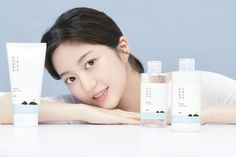 a woman laying on her stomach next to five bottles of skin care products in front of her