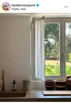 two baskets sit on the counter in front of an open window with white drapes