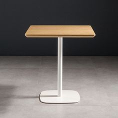 a wooden table sitting on top of a white pedestal