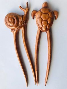 two wooden spoons shaped like animals on top of each other, one with a shell and the other with an animal's head