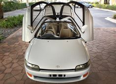 a white sports car parked in front of a building with its hood up and the door open