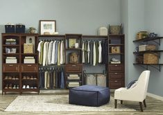 an organized closet with clothes, shoes and other items on shelves next to a footstool