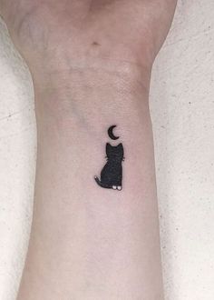 a small black cat with a crescent moon tattoo on the left inner arm and wrist