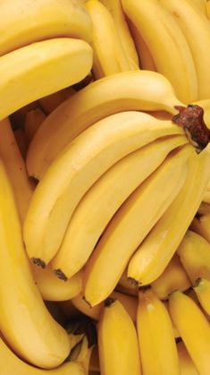 bunches of yellow bananas are piled together