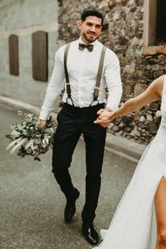 a bride and groom walking down the street holding hands