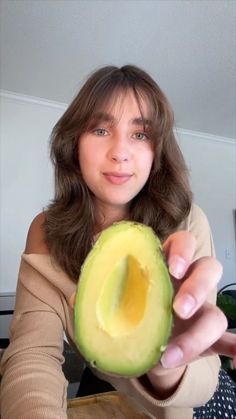 a woman holding an avocado up to the camera