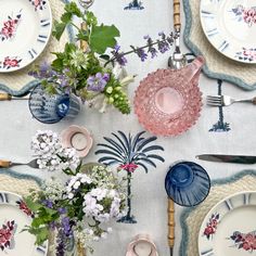 a table topped with plates and vases filled with flowers