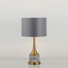 a lamp that is on top of a table with a gray shade over the base