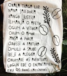 a white tea towel with black writing on it in the middle of some plants and grass