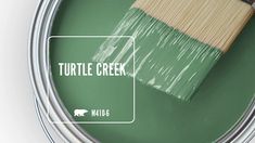 a green paint can with a wooden brush in it and the words turtle creek painted on it