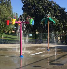 two colorful water fountains in the middle of a park