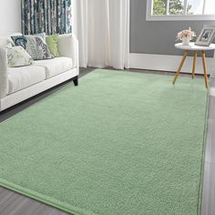 a living room with a white couch and green rugs on the floor in front of a window