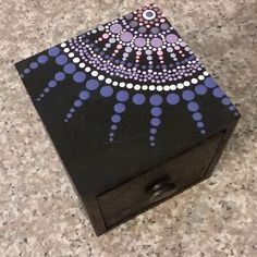 a black box with purple and white designs on it sitting on top of a counter