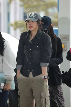 the woman is walking down the street with her hand in her pocket and wearing a baseball cap