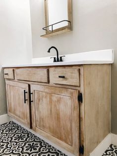 a bathroom with a sink, mirror and black and white floor tiles on the floor