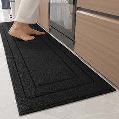 a person standing on a black mat in front of an oven