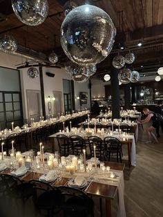 a room filled with lots of tables covered in disco ball lights and plates on top of them