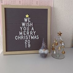 a wooden sign sitting on top of a table next to a christmas tree and decorations