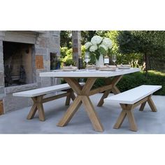 a table with two benches in front of a fire place and vases on it