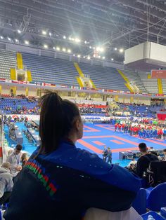 people are sitting in chairs at an indoor wrestling match while others watch from the stands