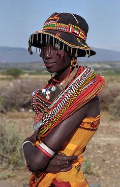 a woman in an elaborately decorated headdress poses for the camera with her arms crossed