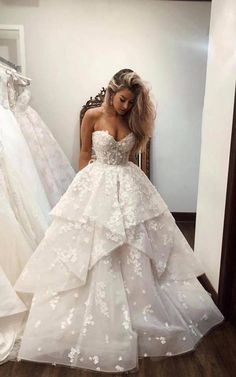 a woman standing in front of a mirror wearing a wedding dress with flowers on it