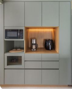 a kitchen with grey cupboards and white tile flooring is lit by recessed lighting