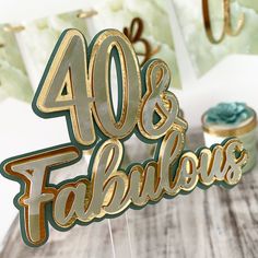 a cake topper that says 40 and fabulous with gold foil lettering on the side