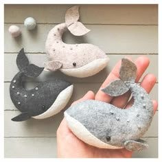 hand holding up three felt whale ornaments in different colors