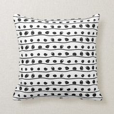 a black and white pillow with an abstract design on the front, featuring small dots