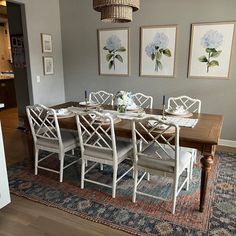 a dining room table with white chairs and blue rug