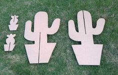 three wooden cutouts of cactus and cacti in the grass